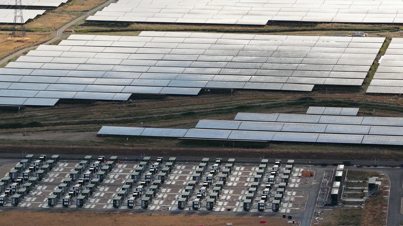 Perspektywa z lotu ptaka na dużą elektrownię fotowoltaiczną i przyległy system magazynowania energii akumulatorowej, kluczowy element dla stabilności sieci i przechowywania odnawialnej energii słonecznej do późniejszego wykorzystania