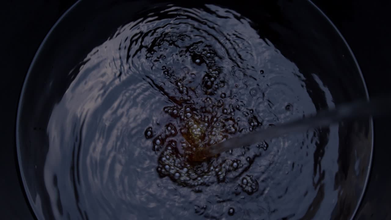 Blurred moving Water spins in the black barrel.