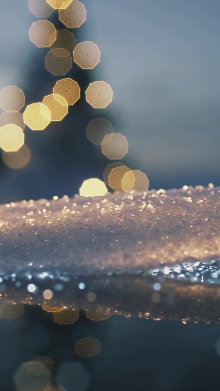 Vertical video: Shifting camera revealing glinting frost and warm bokeh on icy surface showing glow