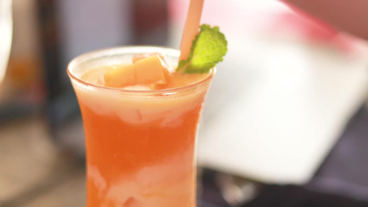 Mano che mescola una rinfrescante bevanda al succo di mango a Phuket, Thailandia