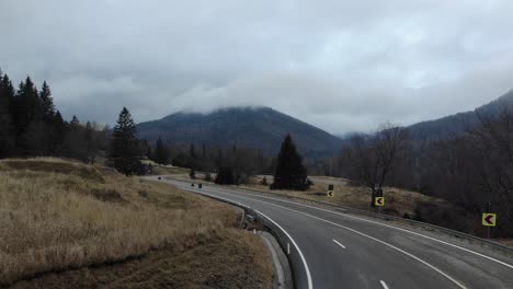 Empty-Concrete-Road-Through-Sloping-Mountains-Under-Gloomy-Sky