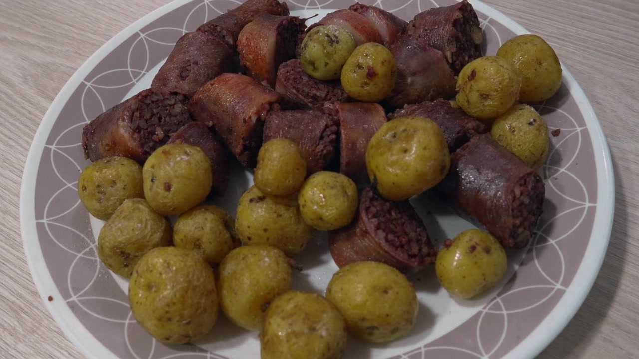 Fette di morcilla cotta e patate novelle condite servite su un piatto accanto a una ciotola di salsa aji tritata su un tavolo di legno