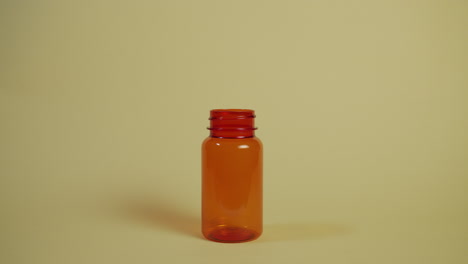 slow motion wide shot of a pill falling vertically into a pill bottle