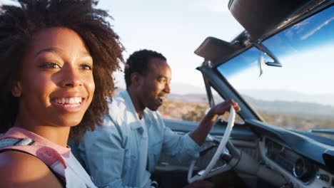 young black couple driving in open car, close up, side view