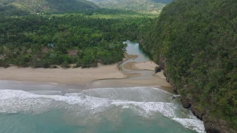 Aerial-view-of-San-Juan-river-meeting-the-ocean-at-white-sand-beach,-Caribbean