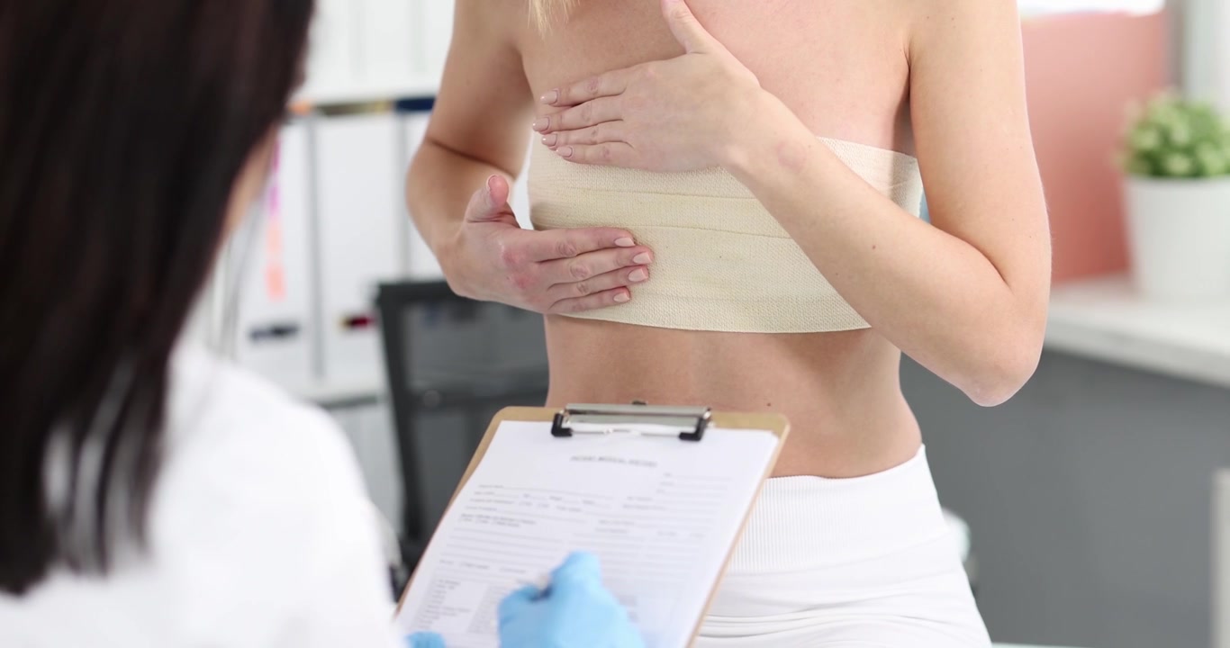 Doctor examines woman complaining after breast augmentation