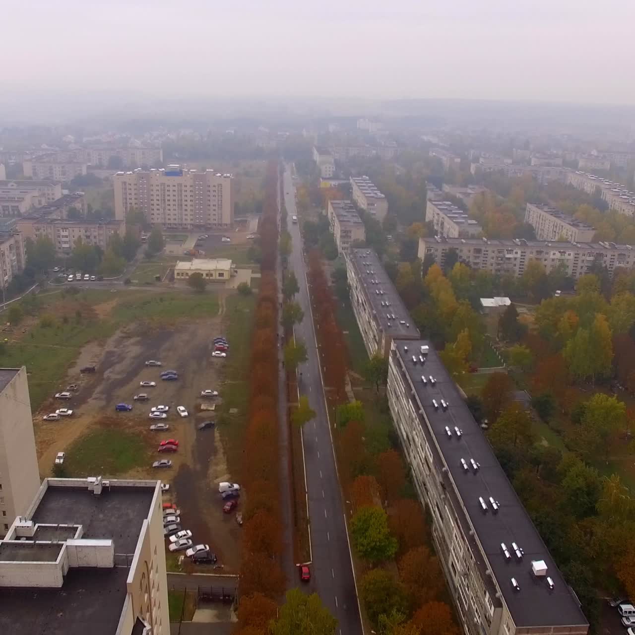 Gloomy autumn sight of the usual provincial city of Ukraine. Drone flyover the residential areas and roads crossing the city. Foggy day background