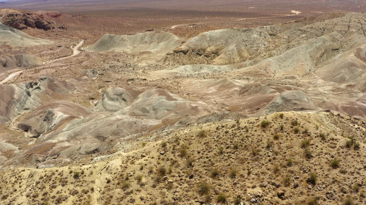 volando sobre una de las grandes formaciones montañosas en la cuenca del arco iris y mirando hacia abajo para ver el valle del desierto debajo
