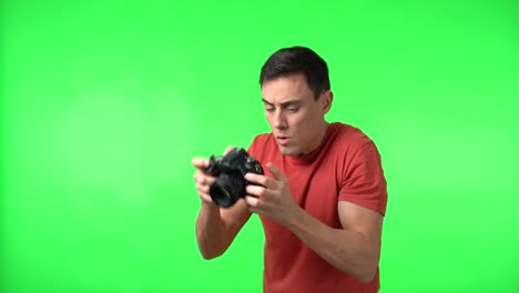 man with surprised expression holding a camera on a green screen