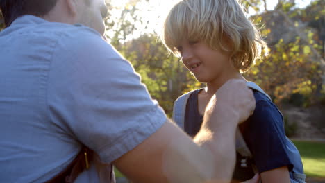 father fastening son's backpack as they get ready for hike