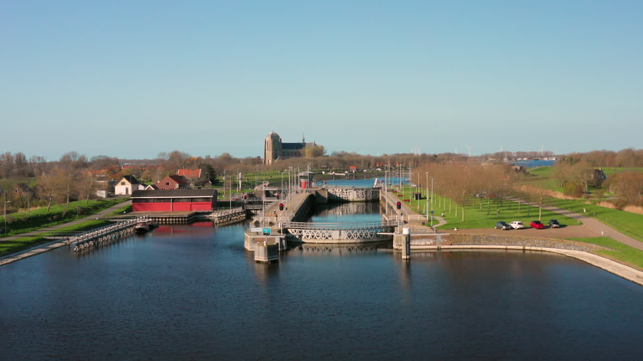Aerial view of a waterway with a bridge, church, and surrounding landscape