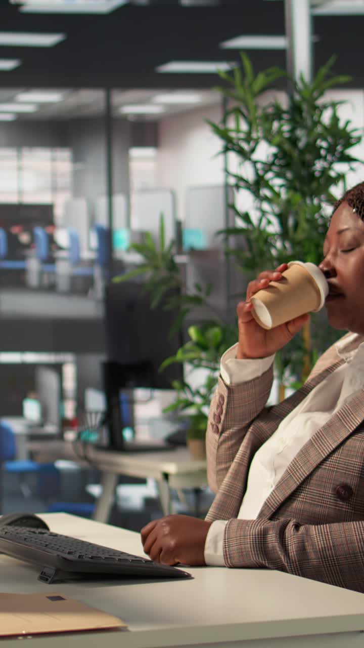 Tired African American Businesswoman Rubbing Eyes and Drinking Coffee in Office