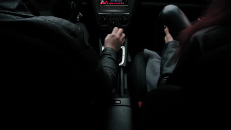 view from the backseat of a man shifting gears in his sport car while his girlfriend is sitting by him