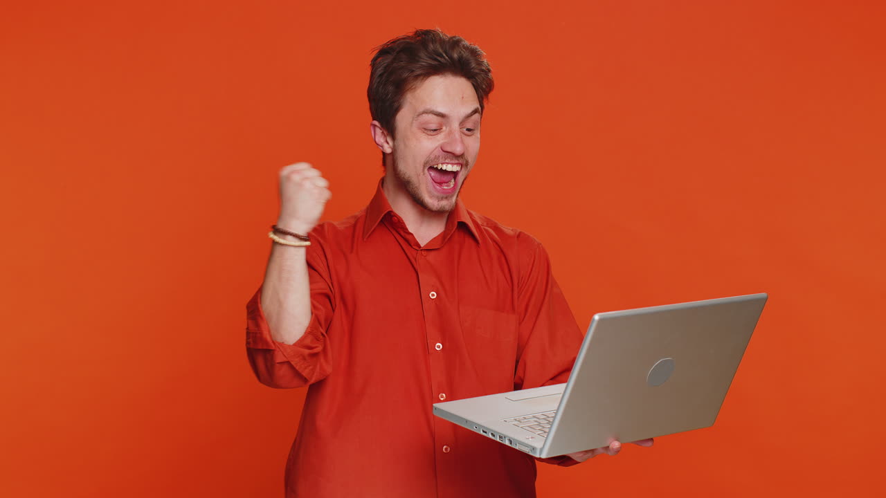 joven feliz trabajando en una computadora portátil ganando un juego de lotería en línea celebrando el éxito victoria