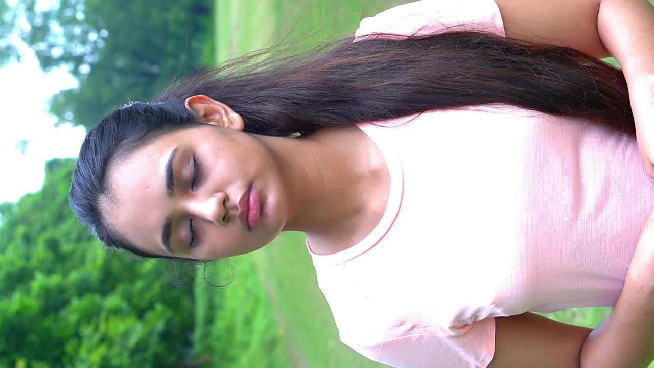 toma vertical de una hermosa joven consciente de la aptitud física parada en el parque con los ojos cerrados y haciendo ejercicio de respiración profunda