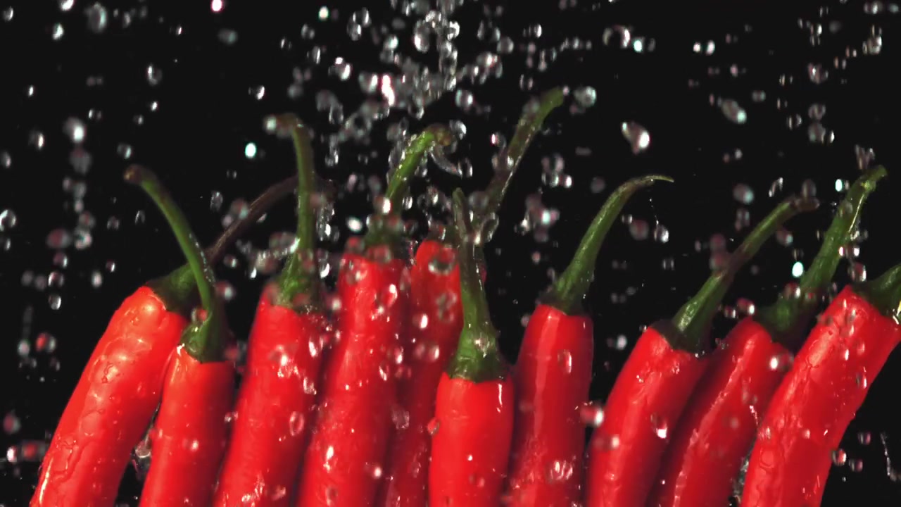 Fresh Red Chili Peppers with Water Drops Splashing in Slow Motion
