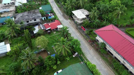 Idyllic-Flyover-Shot-of-Quaint-Asian-Village-Neighborhood-with-lush-tropical-greenery,-schoolhouse-and-underdeveloped-homes