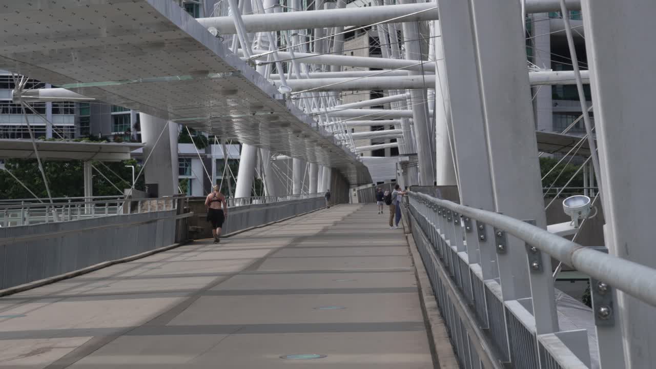 People walking on a modern pedestrian bridge with distinctive architecture