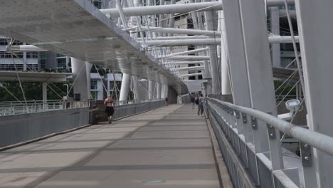 people walking on a modern pedestrian bridge with distinctive architecture