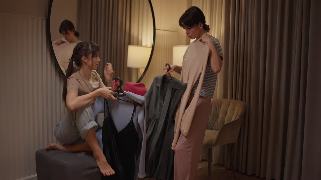 Two women indoors in a room with a mirror and lamp