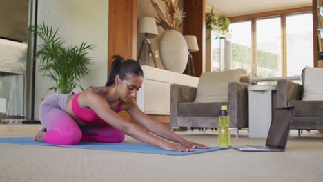 mujer de raza mixta practicando yoga en casa