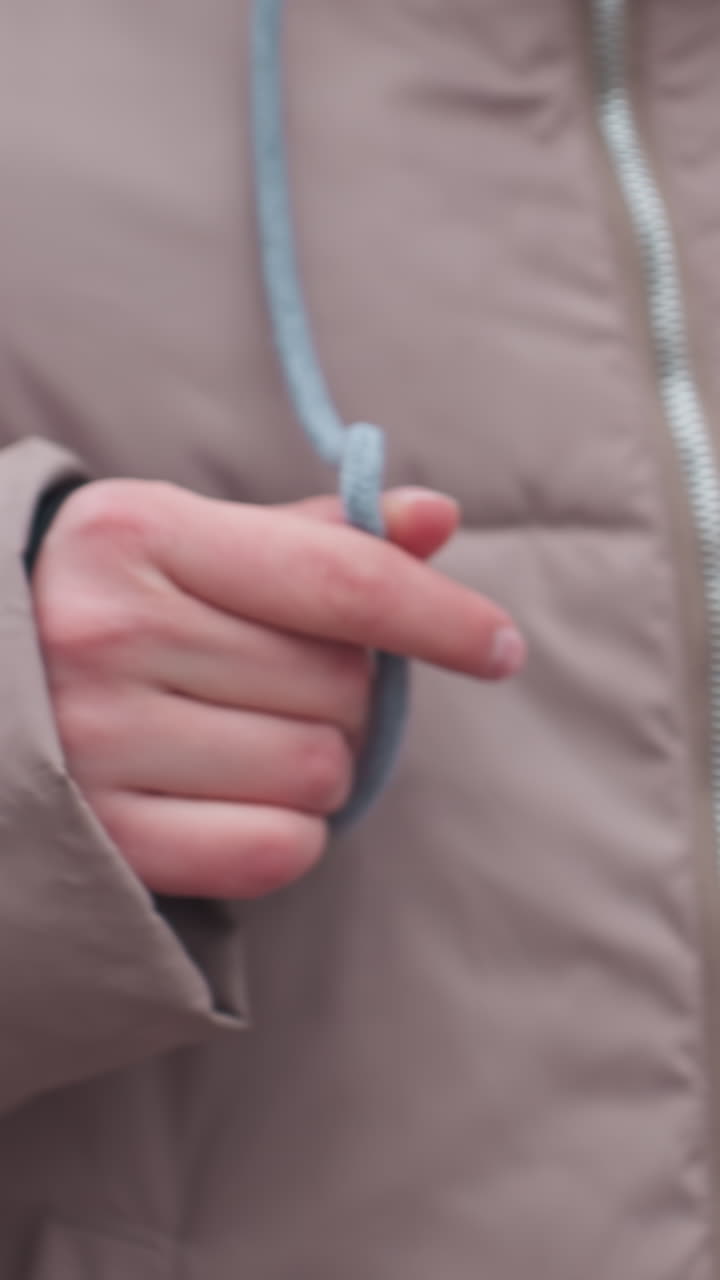 primer plano de una persona balanceándose en traje de invierno, jugando con encaje de capucha mientras agarra la cadena de balanceo, crear un entorno frío al aire libre en un parque durante el invierno