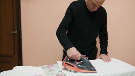 elderly man uses the iron with precision