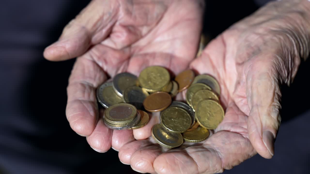 las manos arrugadas de un anciano que sostiene una pila de monedas de euro, un hombre jubilado contando una pensión miserable, un anciano desesperado mirando su bajo presupuesto mensual en las manos.