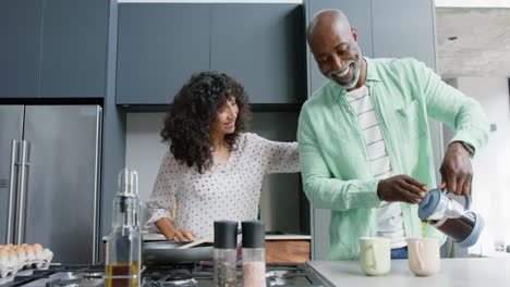 Glückliches-Biracial-Paar-Umarmt-Und-Gießt-Kaffee-In-Der-Küche-Ein,-Zeitlupe