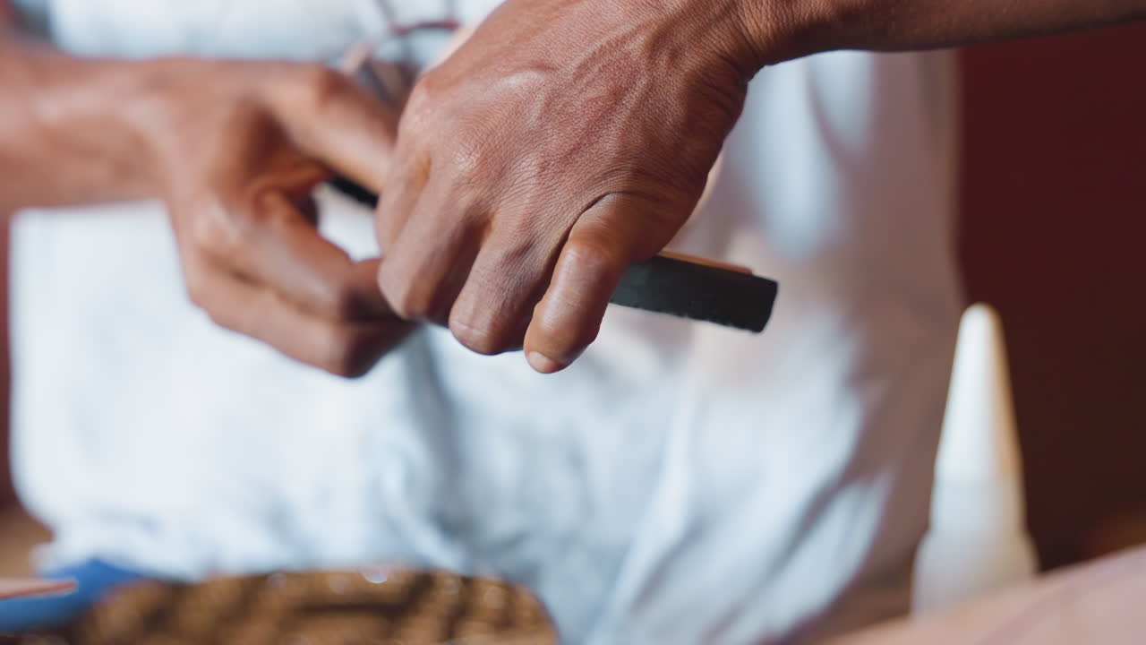 Tangan merakit sol sandal kulit dengan perekat, pemandangan bengkel close-up yang menunjukkan bekas alat, penyelarasan hati-hati, aplikator botol, sol luar bertekstur, dan teknik pengrajin yang metodis.