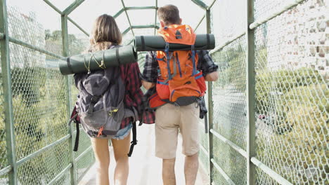 un par de viajeros caminando por un puente con vallas de seguridad