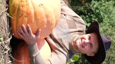 a young farmer with a smile on his face hugs a big ripe yellow pumpkin a young farmer with a smile on his face hugs a big ripe yellow pumpkin autumn harvest