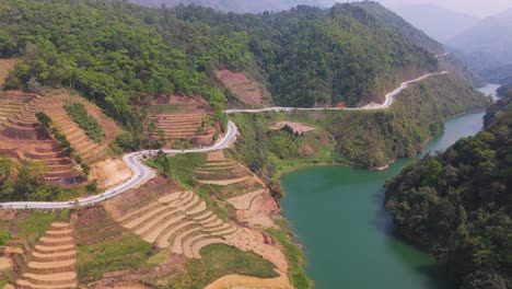 aerial view of winding mountain road along rice terraces and river