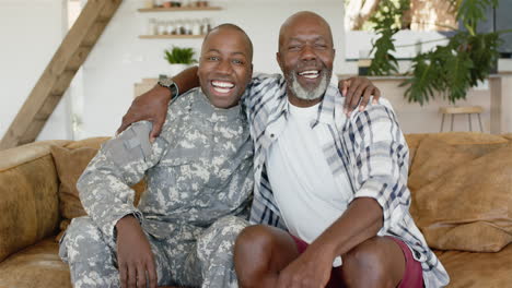 smiling military father sitting on couch, hugging older father in casual clothes