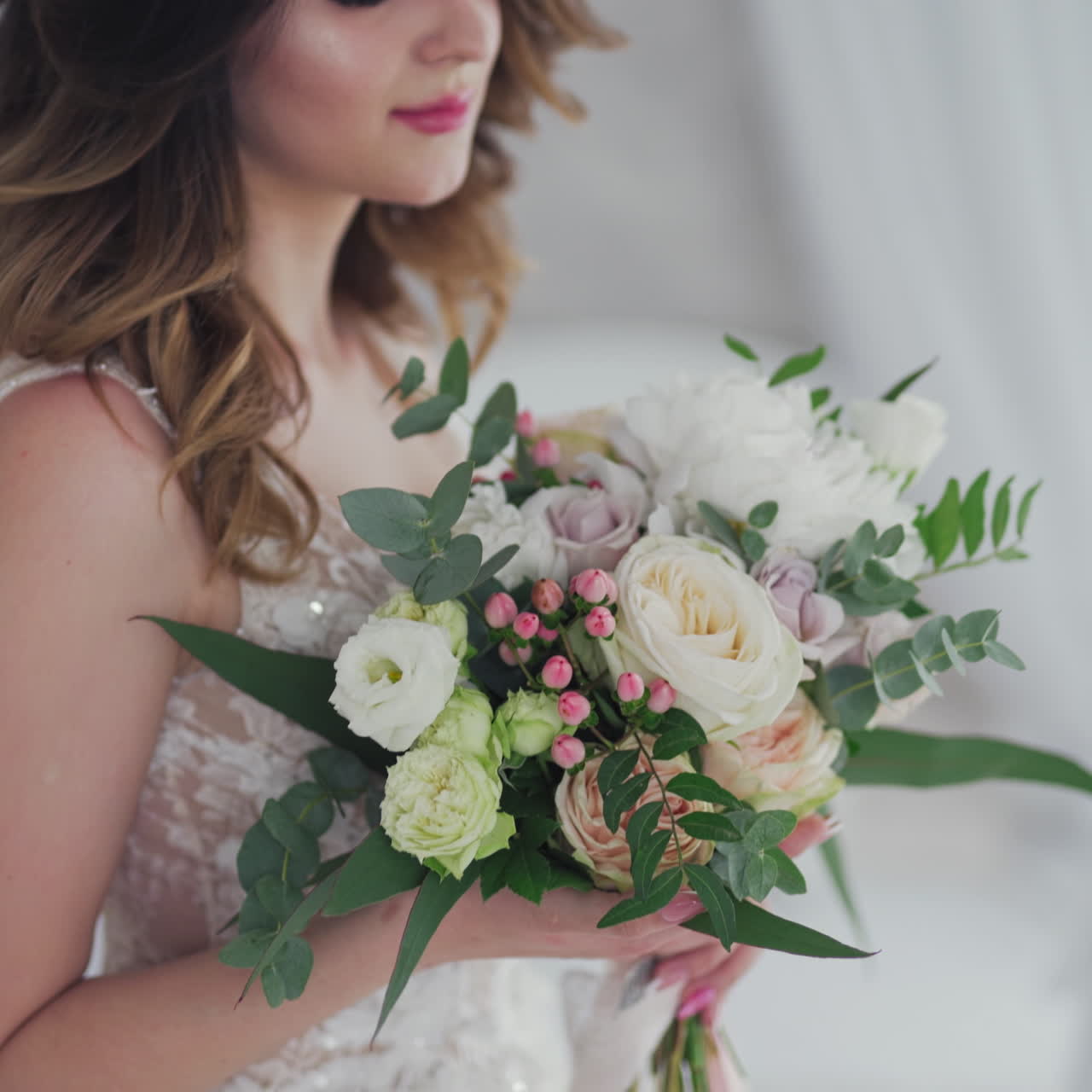Attractive bride in fancy white wedding dress with stylish bunch of flowers. Wedding day of bride in bridal gown. Beauty woman and bouquet. Portrait of a model in a beautiful bridal dress.