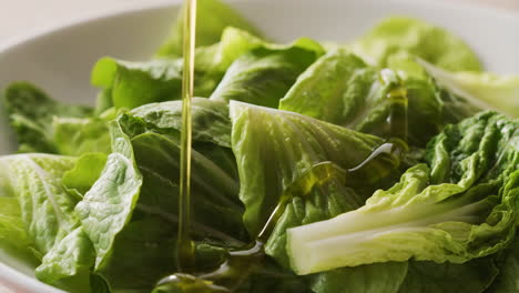 pouring olive oil over fresh green lettuce