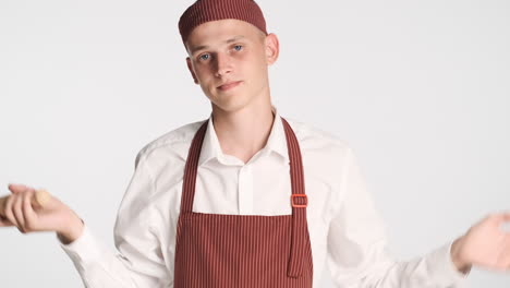 doubtful man in baker uniform holding rolling pin