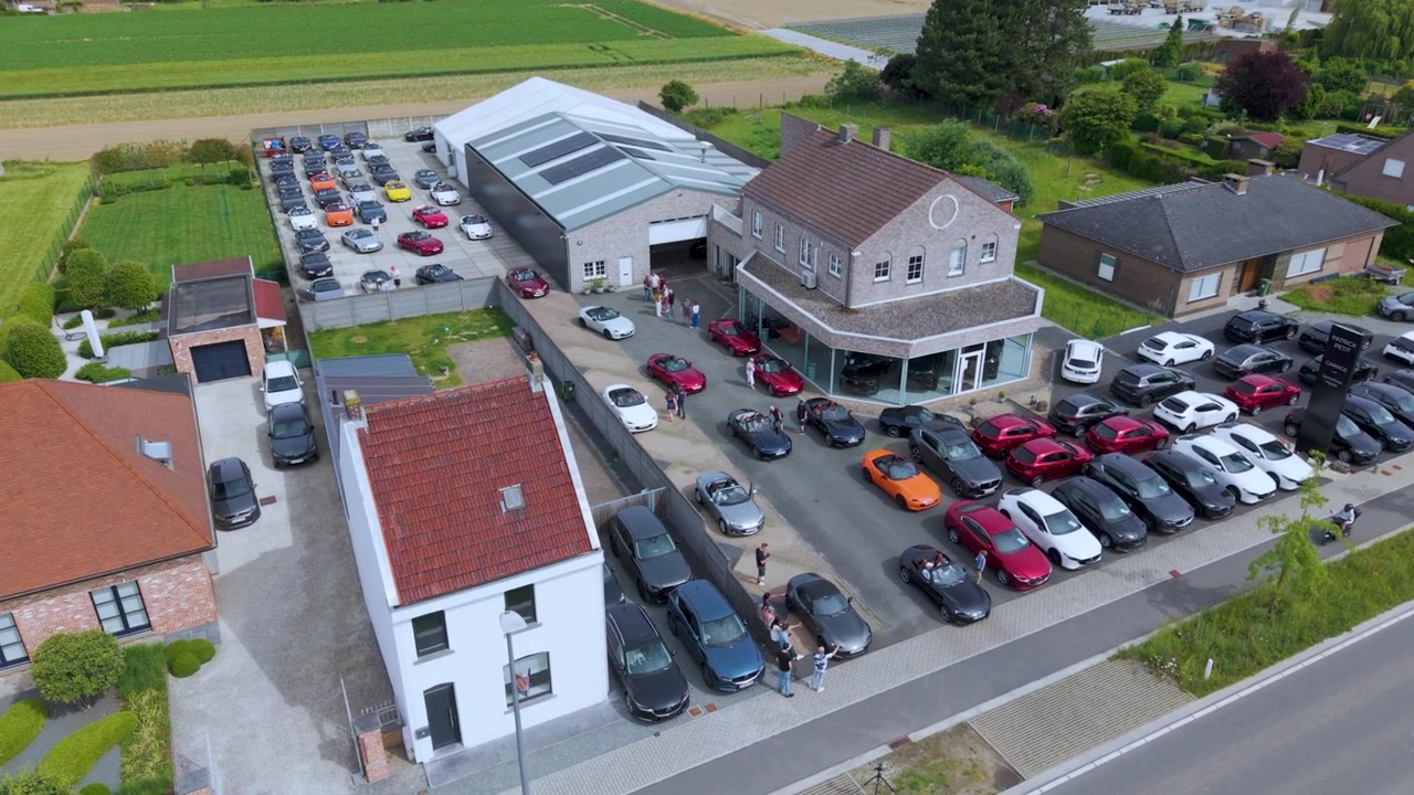 Orbita aerea cattura una concessionaria d'auto, un'area parcheggio e le strade vicine dall'alto. Il movimento fluido del drone offre un'ampia panoramica della proprietà e dell'area circostante.