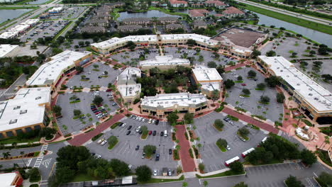 wide aerial pan of busy outdoor shopping plaza - slow tracking pan with view of parking lot