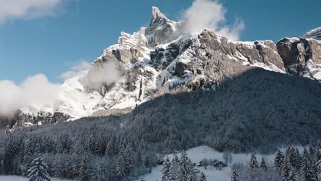 una vista aérea del cirque du fer à cheval mientras está cubierto de nieve durante un frío invierno, volando hacia atrás e inclinándose hacia abajo desde el pico tenneverge cubierto por el sol hacia las pistas de esquí nórdico vacías