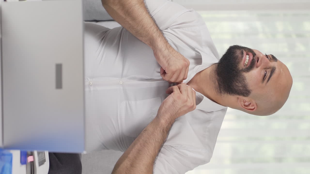 video vertical de un hombre que trabaja en una oficina en casa se está asfixiando por el calor.