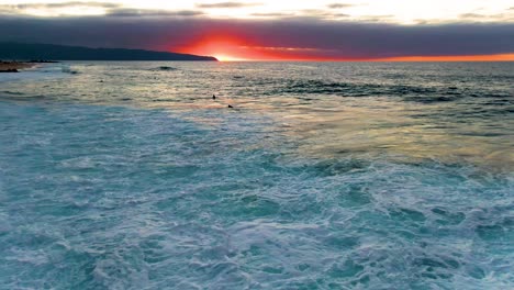 Silhouette-of-surfers-in-powerful-Pacific-ocean-waves-in-Hawaii,-aerial-view