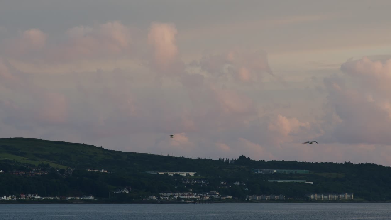 Panoramic View of a Coastal Town and Hills at Dusk