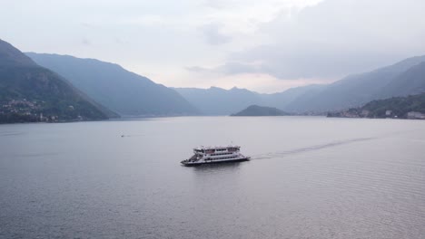 passenger ferry boat on picturesque lake como, with italy alps mountains in background, aerial with copy space