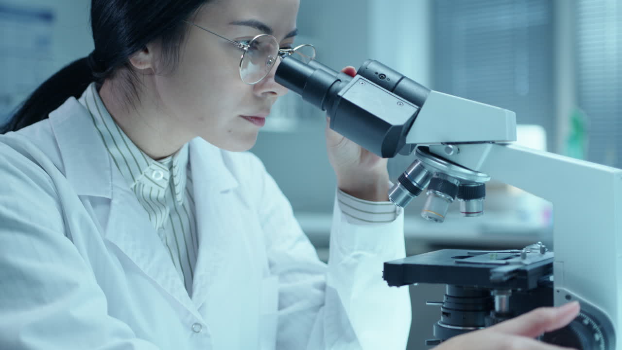 Female Doctor Working with Compound Microscope in Medical Laboratory