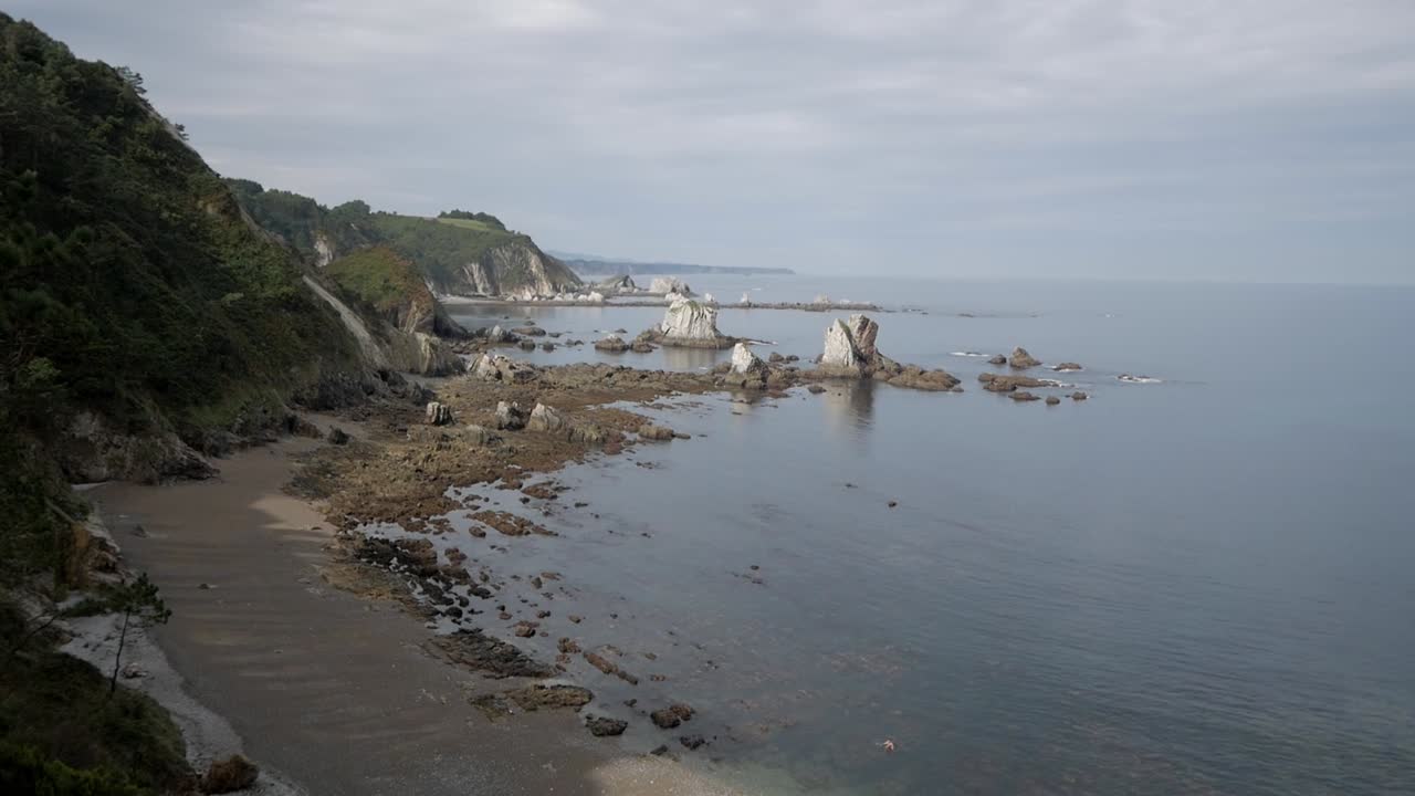 A quiet rocky beach with isolated rock formations and calm waters at Playa del Silencio