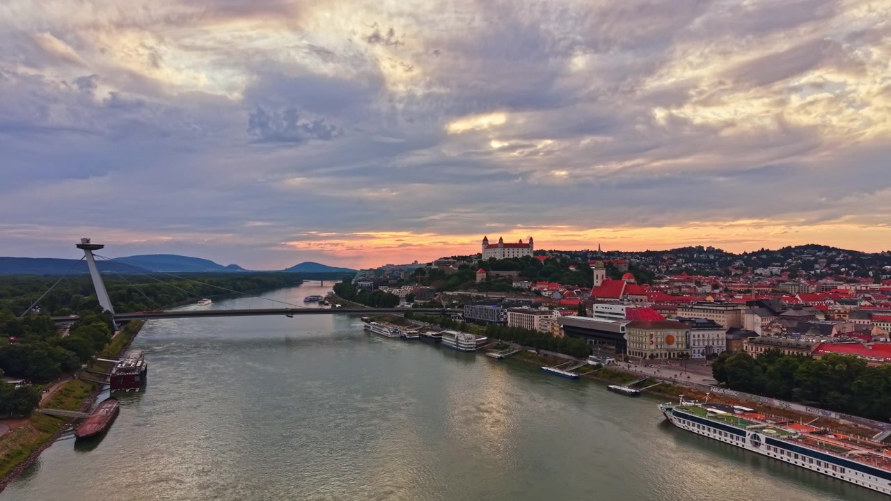 Solnedgang over Bratislava by med Donau-floden og ikoniske vartegn synlige i baggrunden
