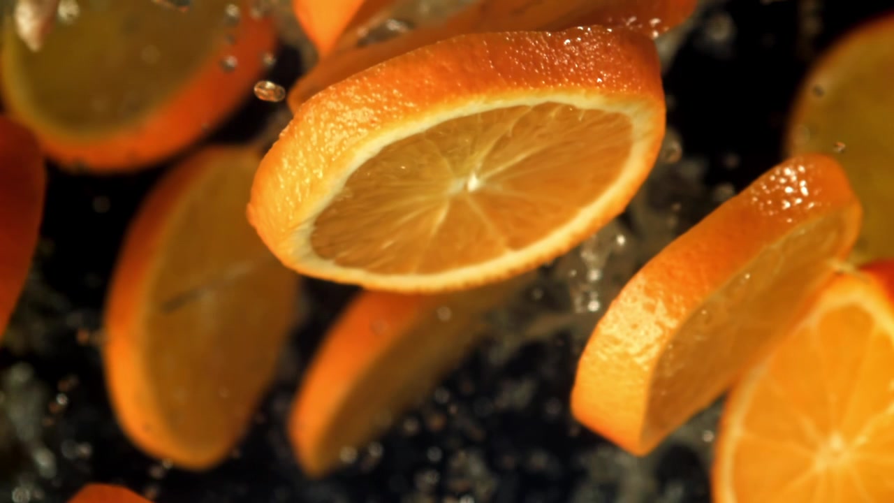 Fette d'arancia fresche che schizzano acqua al super rallentatore