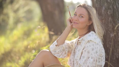 happy girl artist paints a picture on the background of summer nature hobbies creativity - happy girl artist paints a picture on the background of summer nature. a woman with a brush and a palette makes a sketch. hobbies, creativity, leisure time