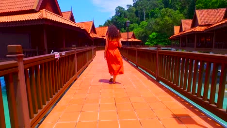 mulher caminhando no cais de uma casa de palafitas na ilha de langkawi